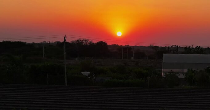 Stunning aerial view of a rural village surrounded by patchwork farmland during a golden sunset in Gujarat, India.