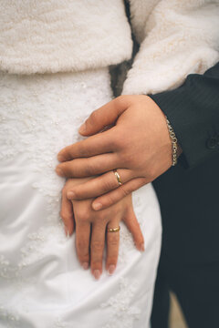 Couple's hands wearing engagement and wedding rings, symbolizing love, commitment, and marriage. A close-up view of joining hands