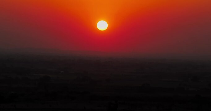 Stunning aerial view of a rural village surrounded by patchwork farmland during a golden sunset in Gujarat, India.