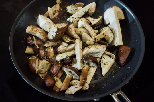 Porcini mushrooms and herbs cooking in a pan
