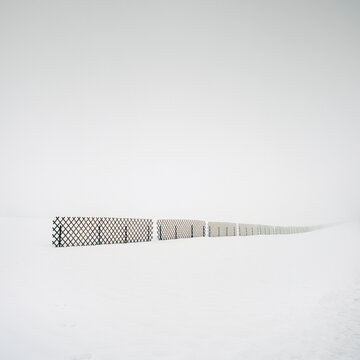 Fence line surrounded by snowcovered landscape below white sky, Frankenmarkt, Austria
