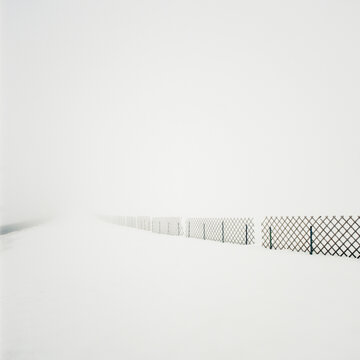 Fence line surrounded by snowcovered landscape below white sky, Frankenmarkt, Austria
