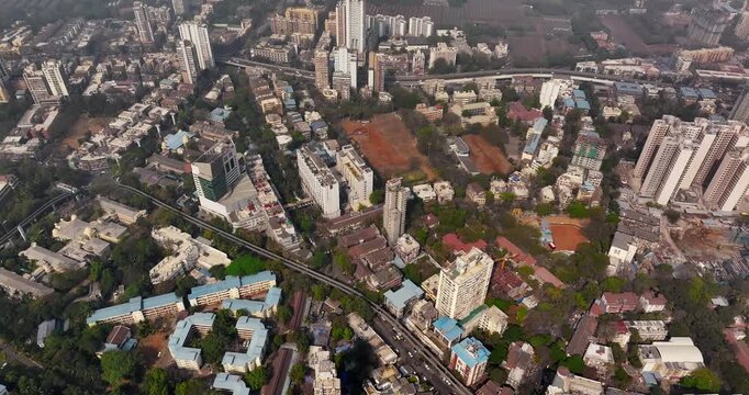 Cinematic aerial view of the Mumbai city skyline during the monsoon season, with dramatic clouds creating a moody and atmospheric backdrop.