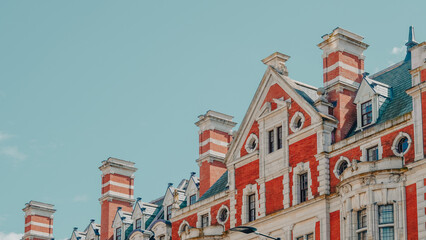 Historic red brick building with ornate architecture against blue sky © Наталья Добровольска