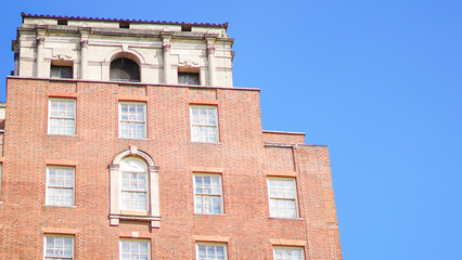 Historic brick building exterior with windows against clear blue sky © Наталья Добровольска