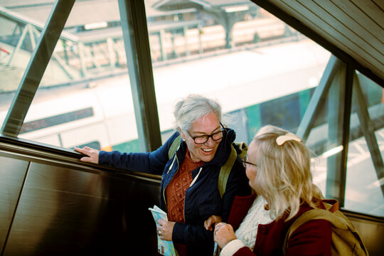 Happy senior women traveling on escalator at train station