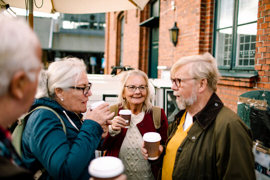 Senior friends drinking coffee on city street