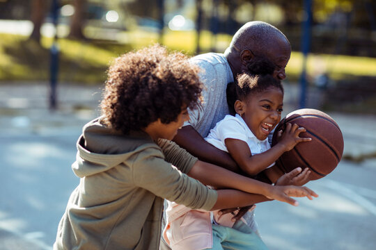 Grandfather and children playing basketball at park