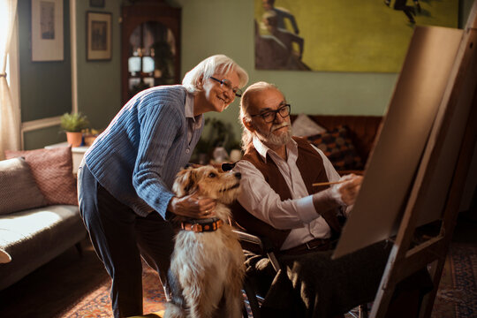 Senior couple painting at home with dog