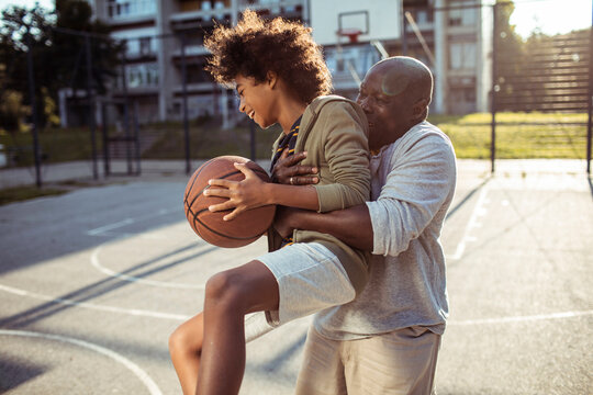 Father and son playing basketball on outdoor court