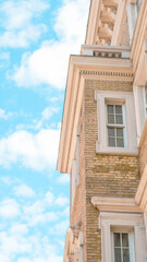 Obraz premium Corner view of historic brick building against a bright blue sky