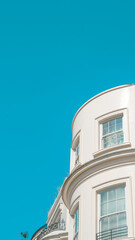 Obraz premium Curved white building facade against clear blue sky in urban setting