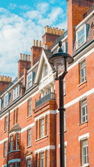 Fototapeta premium Red brick residential building with lamppost under blue sky