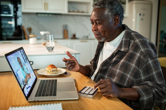 Senior man on telehealth video call in home kitchen