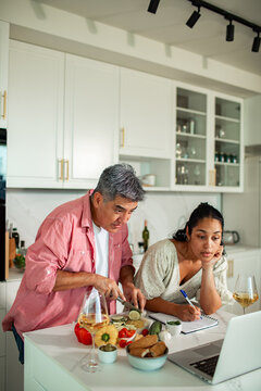 Couple following online recipe cooking together in modern home kitchen