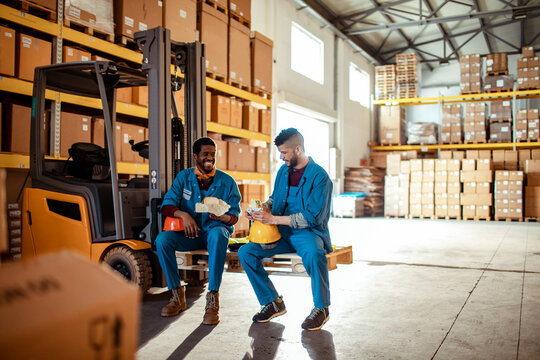 Two warehouse workers taking a lunch break by forklift