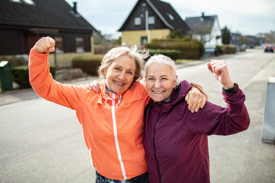 Two senior women celebrating fitness on suburban street