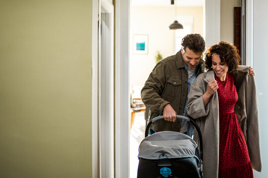 Happy parents arriving home with newborn in car seat