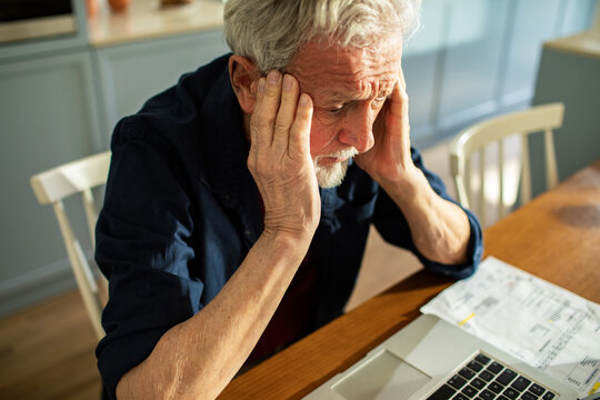 Stressed senior man reviewing bills at home