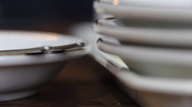 Ant crawling between stacked white plates on a wooden table. Minimal scene with subtle movement, ideal for hygiene, pest control, or food safety concepts.
