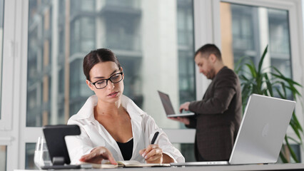 Fototapeta premium Woman using laptop for business tasks in modern office space. Corporate concept. 