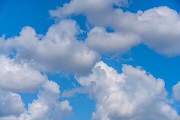 Fototapeta premium Blue sky with scattered white clouds forming soft shapes, creating minimal and airy composition. Concept of freedom, weather, calm atmosphere