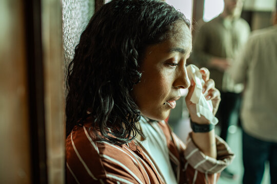 Young woman wiping tears at group therapy session