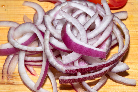 Close up of finely chopped sliced red onion salad vegetables on wooden chopping board