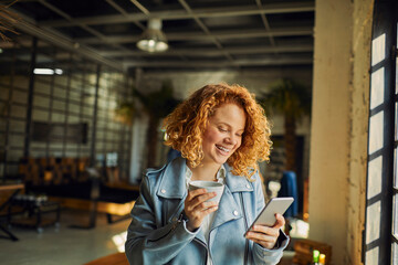 Fototapeta premium Smiling woman using smartphone in cozy cafe