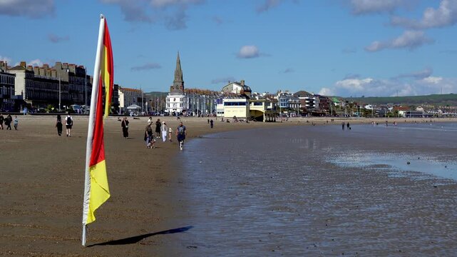 Weymouth,Dorset, UK, 31st March 2026 - Lifeguard flags blowing on Weymouth beach with town in B/G