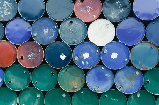 Old chemical barrels. Blue, green, and red oil drum. Steel oil tank. Toxic waste warehouse. Hazard chemical barrel with warning label. Industrial waste in metal drum. Hazard waste storage in factory.