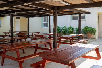 Fototapeta premium Wooden picnic tables under covered shelter in campsite park outdoor dining area travel and leisure concept