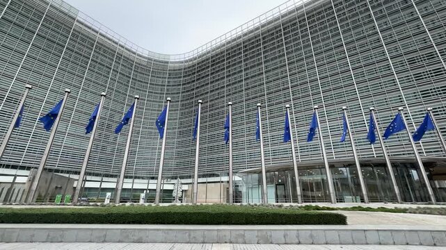Wide shot of the European Commission building in Brussels with European Union flags, symbolizing politics, governance, and international institutions.