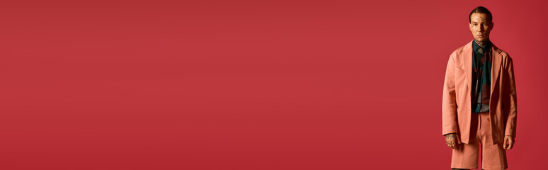 Stylish young man stands confidently against a vibrant red backdrop © Bliss