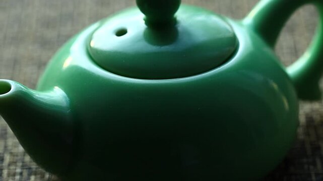 A green teapot sits on a table with a clean and simple background