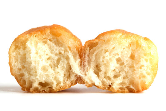 Closeup broken piece golden brown fried dough, baursak or donut showing airy, porous, and soft white interior.