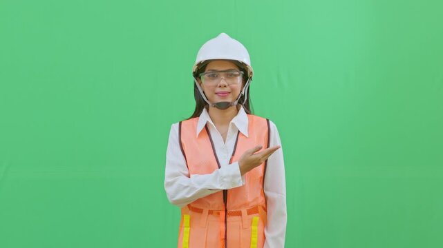 Female worker pointing at the blank chest area of her safety vest where a company logo would be. Perfect for corporate branding and identity videos.