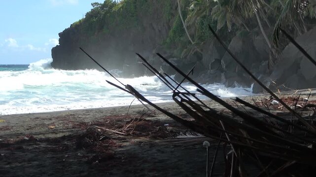 Brandung an einem dunklen Vulkanstrand mit Steilk&uuml;ste