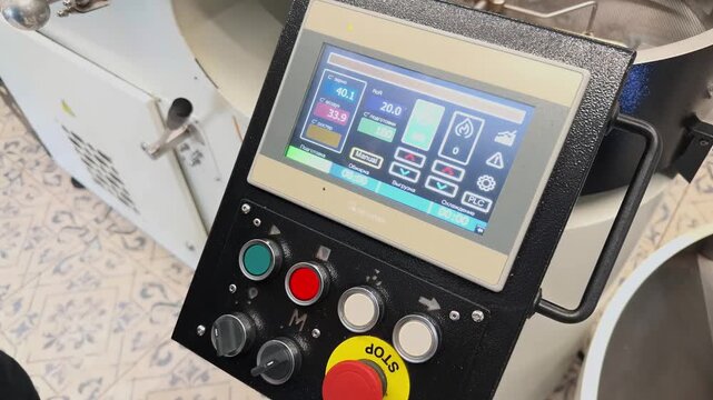 Close Up Camera Approach to Industrial Coffee Roaster Control Panel with Touchscreen Interface Displaying Real Time Temperature Data RoR Parameters and Emergency Stop Button inside Roastery