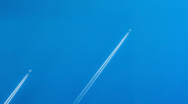 Airplane with white condensation tracks. Jet plane on clear blue sky with vapor trail. Travel by airplane concept. Trails of exhaust gas from airplane engine. Aircraft with white stripes.