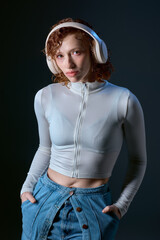 Curly haired young woman immersed in music while relaxed in a studio setting
