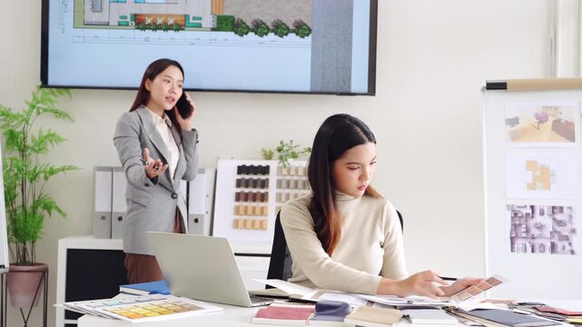 Creative female designer works on design draws sketches in notebook  choosing material and  making interior design surrounded by samples material and stationery