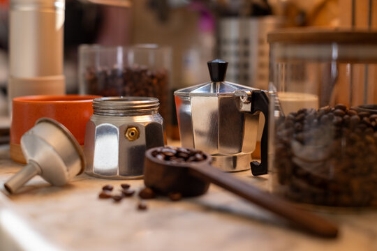 Ingredients for making coffee. Moka coffee maker, coffee grinder with coffee beans are on the table of a cozy kitchen.