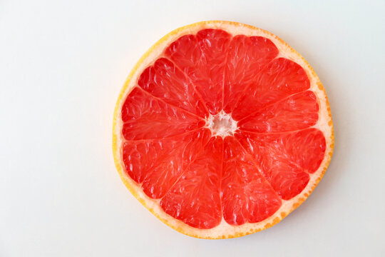 Freshly cut grapefruit slices isolated on white background, bright pink citrus fruit pieces with juicy texture, healthy natural food concept.