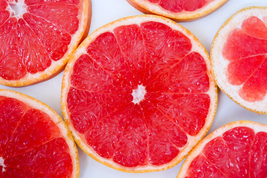 Freshly cut grapefruit slices isolated on white background, bright pink citrus fruit pieces with juicy texture, healthy natural food concept.