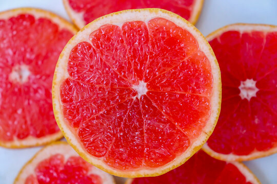 Freshly cut grapefruit slices isolated on white background, bright pink citrus fruit pieces with juicy texture, healthy natural food concept.