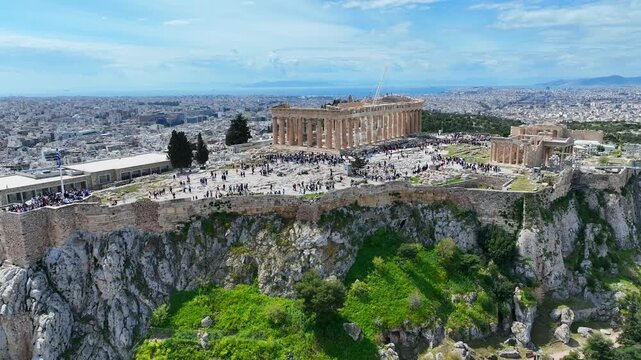 Aerial drone cinematic video of iconic Acropolis hill and the Parthenon a true ancient monument of Western Civilization with beautiful clouds, Athens historic center, Attica, Greece