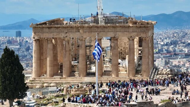 Aerial drone cinematic zoom rotational video of the Parthenon built on top of Acropolis hill a true symbol of ancient world civilization and Greek flag waving, Athens historic centre, Attica, Greece