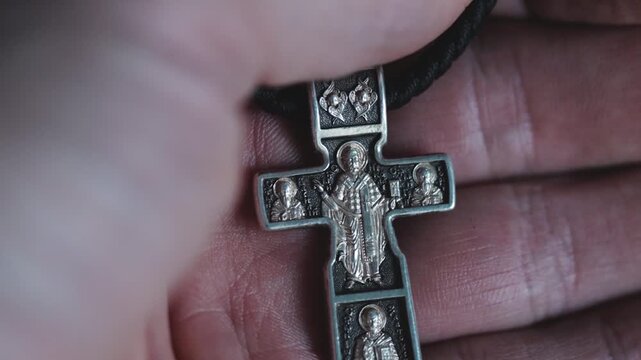 A person grasping a silver cross in their hand