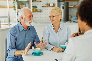 Obraz premium Senior couple having a meeting with an agent, businesswoman, salesperson or doctor in his office
